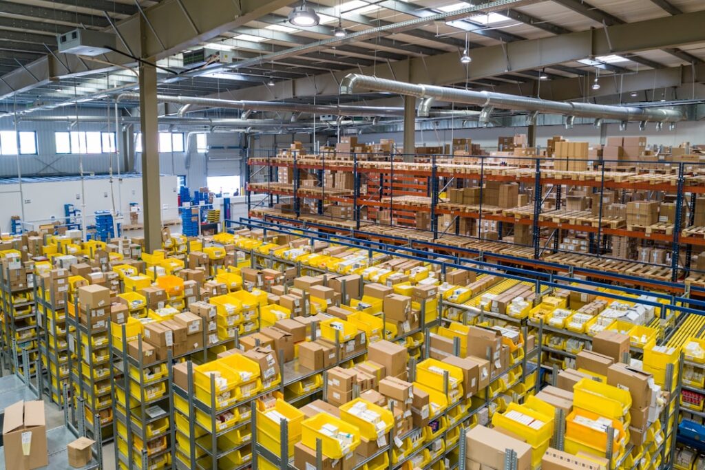Large industrial parts warehouse with organized shelving racks and stocked inventory boxes, representing a marine spare parts distribution facility