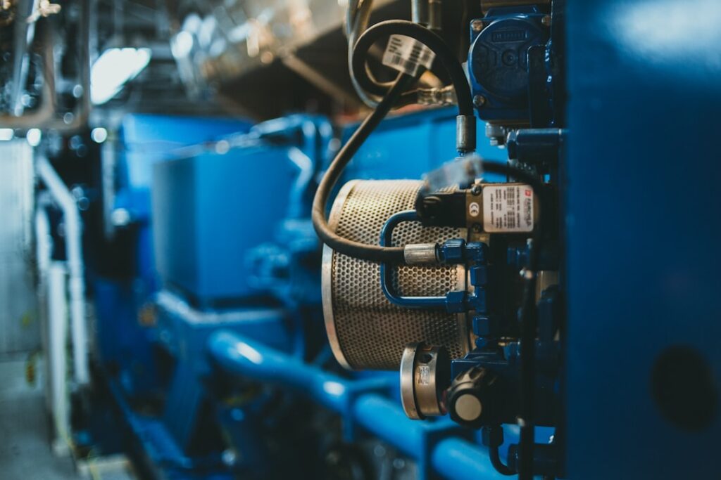 Close-up of a marine engine lube oil filter canister on a blue marine diesel engine in a ship engine room.