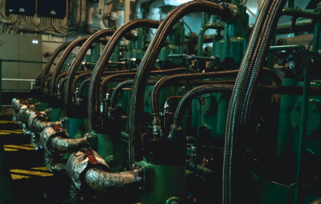 Ship engine room showing main engine exhaust manifolds and piping — legacy Cat 3406 and 3412 service environment