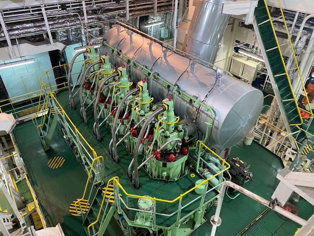 Aerial view of a large two-stroke marine main engine with cylinder covers inside a ship's engine room