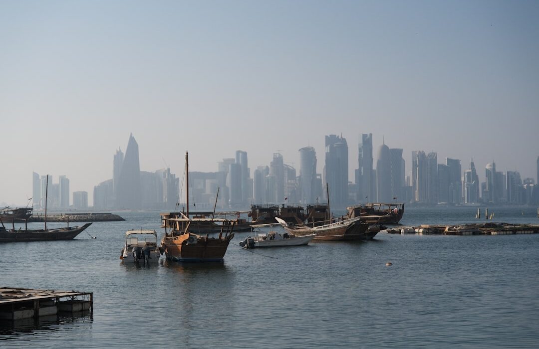 Traditional Gulf dhow vessels moored in a harbor with a Middle East city skyline in the background, representing marine fleet operations in the Gulf region