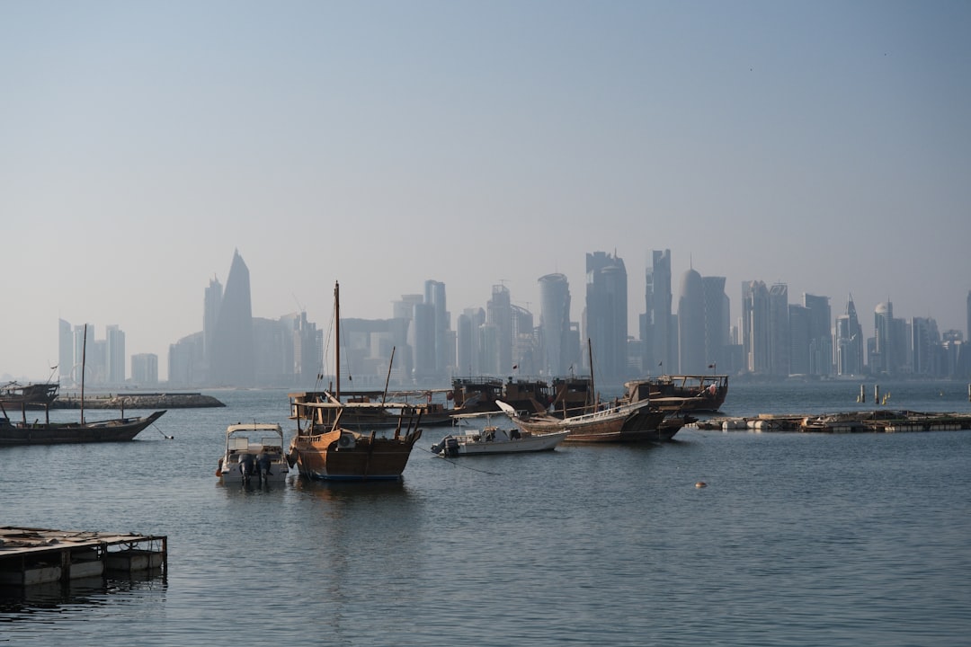 Traditional Gulf dhow vessels moored in a harbor with a Middle East city skyline in the background, representing marine fleet operations in the Gulf region